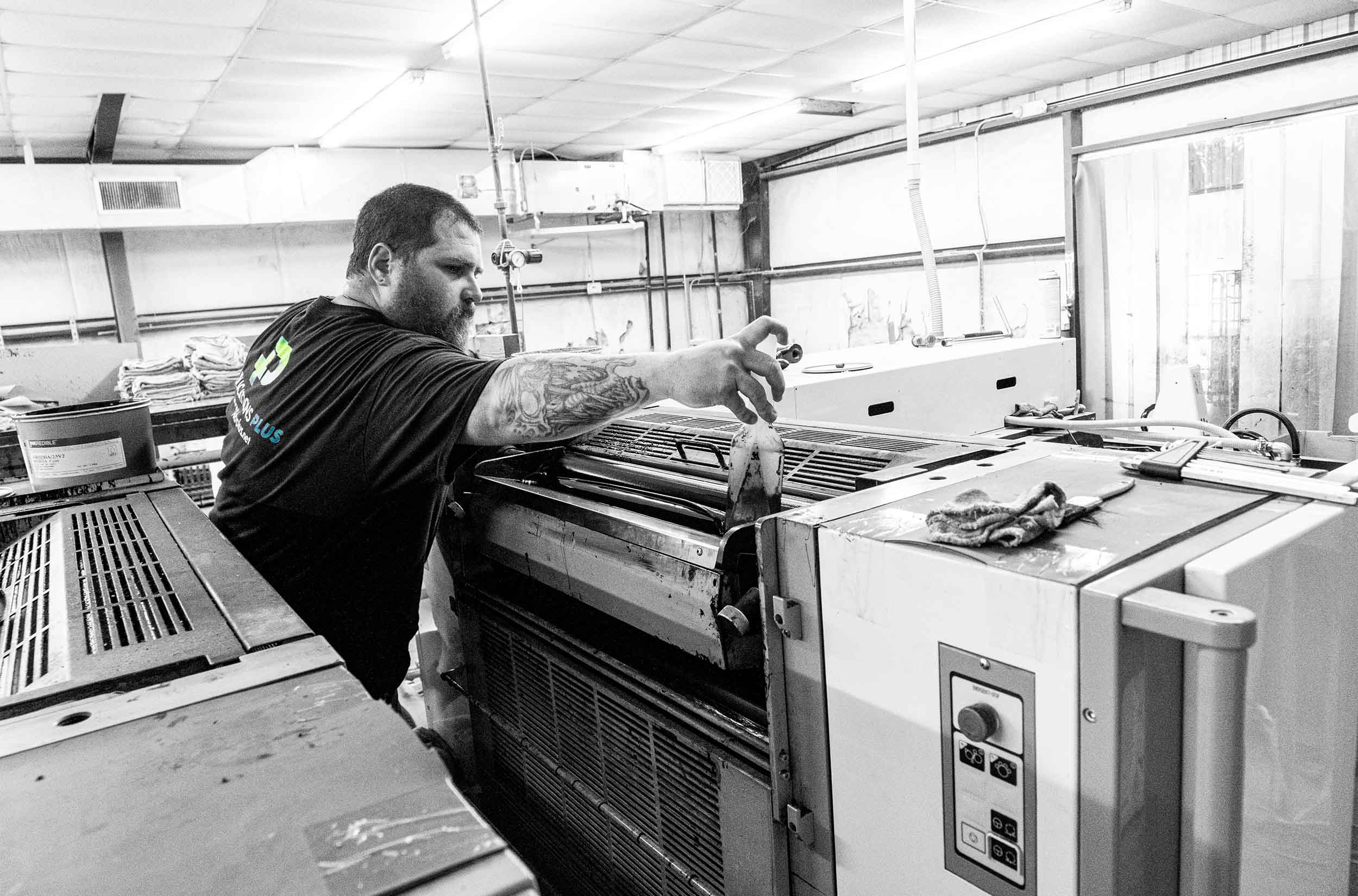 Man opperating shee-fed printing press.